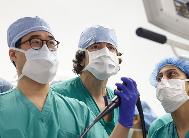 Photo of medical professionals looking at monitor while performing surgery